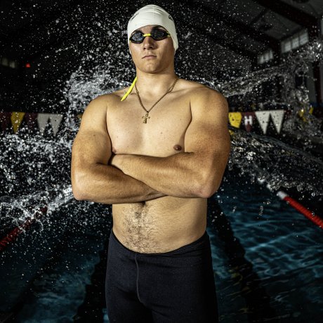 A swimmer takes a posed shot with water splashing behind him.