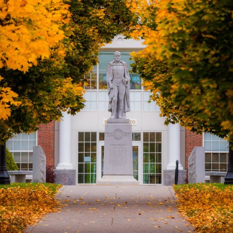 Statue of Captain Alden Partridge framed by vibrant autumn foliage, located at Norwich University.