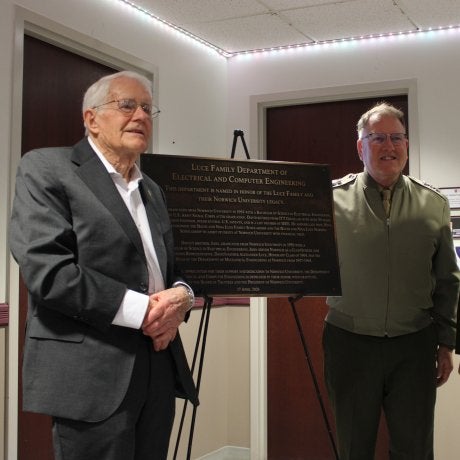 Three people stand beside a plaque for the Luce Family Department of Electrical and Computer Engineering.