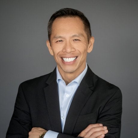 Hansen in suitcoat and blue shirt with arms crossed