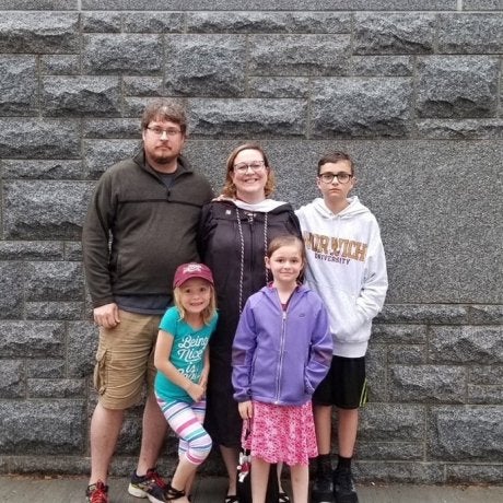Shannon Murphy poses with four people in front of a gray stone wall.