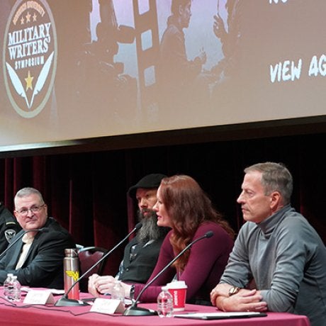 Four panelists sit behind microphones at the Norwich University Military Writers Symposium.