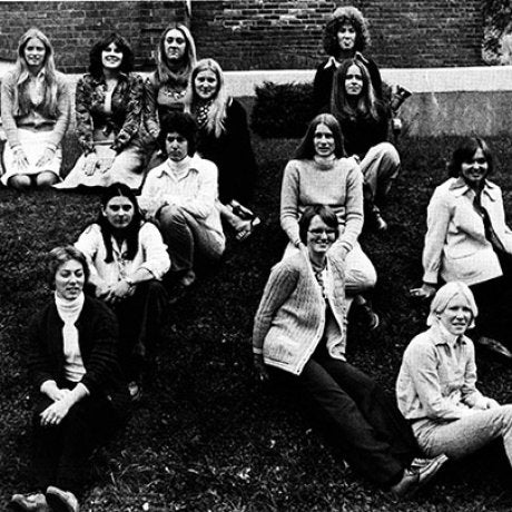 A group of people pose together on a grassy slope in a black-and-white photograph.