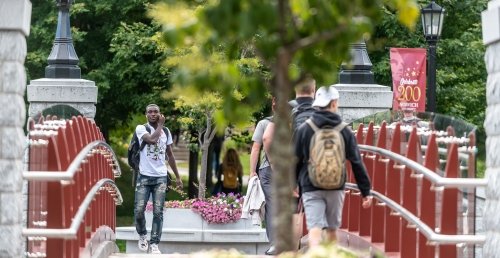 Norwich University students walking across the alumni bridge on campus.