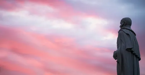 Alden Partridge statue from side, with magenta sunset sky background