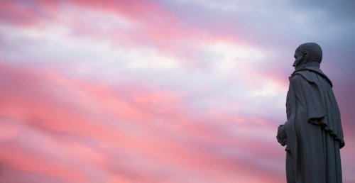 Alden Partridge statue from side, with magenta sunset sky background