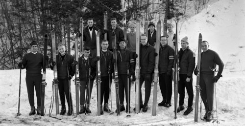 eleven skiers and coach at base of ski hill