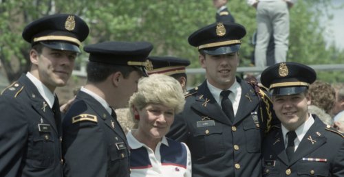four Norwich cadets at their 1986 commencement ceremony surround an older woman.