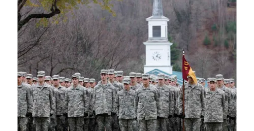 a large number of Norwich Cadets in review formation stand with a chapel steeple in the background.