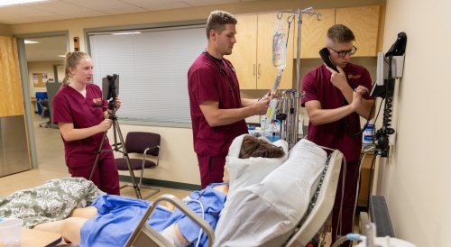 Nursing students working in Norwich's sim lab that replicates a hospital room.