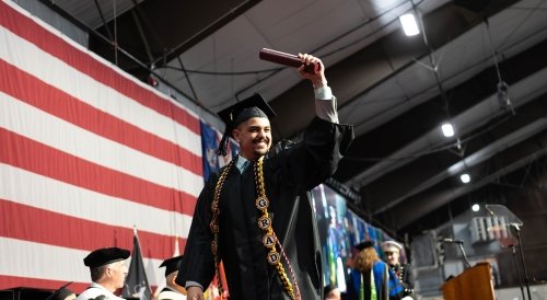 Norwich Graduate Crossing stage holding up diploma