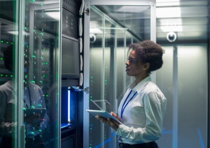 cybersecurity professional works on a tablet in a data center