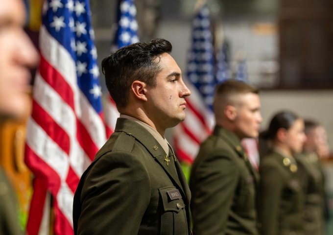 Norwich students commissioning into the Army and standing in front of American Flags in a row.