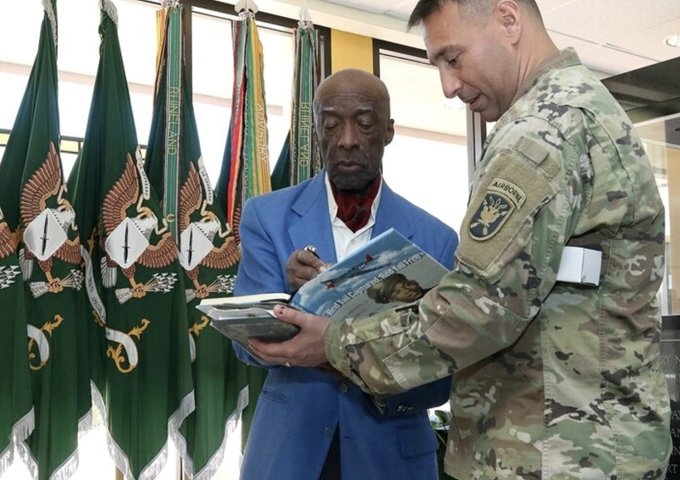 Retired Lt. Col. Enoch Woodhouse II signs a book about the Tuskegee Airmen for U.S. Army Lt. Col. Eric Marella, a reserve component personnel branch chief, following a Feb. 25, 2019, speech in Fort Bragg, North Carolina.