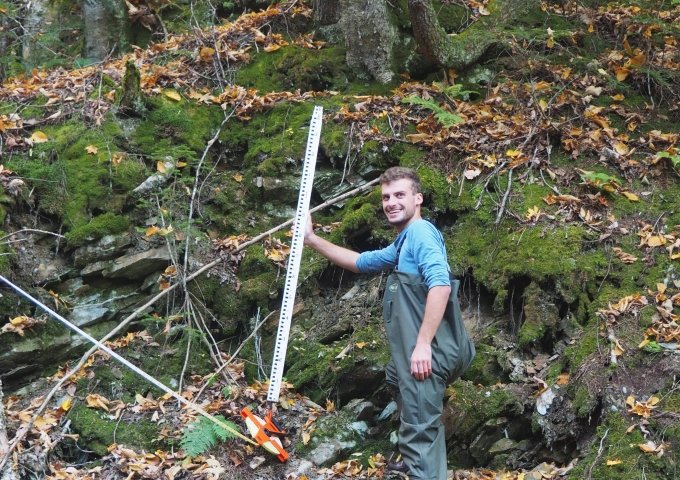 EES student outside in the woods taking measurements.