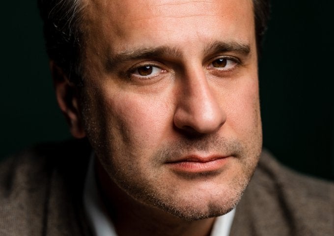 Close-up portrait of Simon Shuster against a dark background.