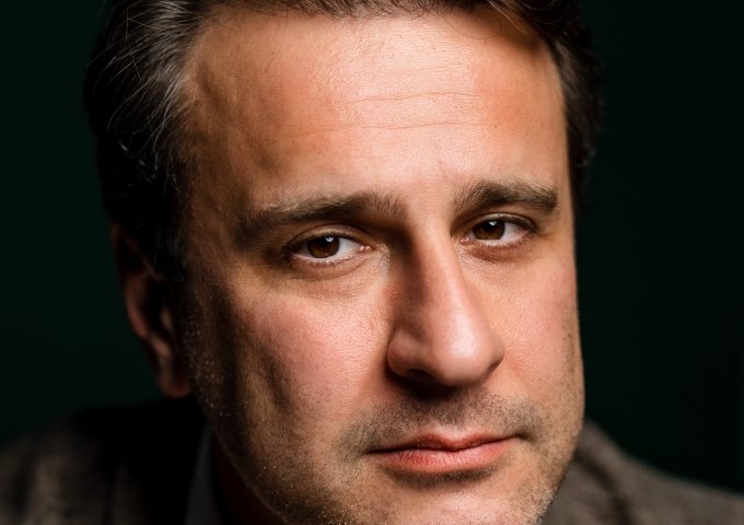 Close-up portrait of Simon Shuster against a dark background.