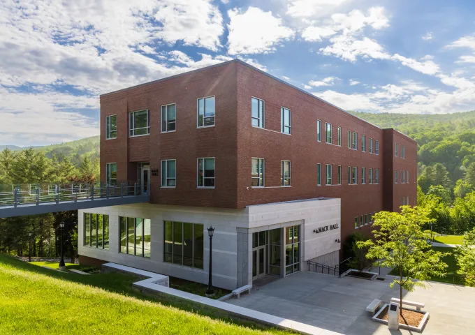 Mack Hall, large rectangular building, with the Green Mountains in the background.