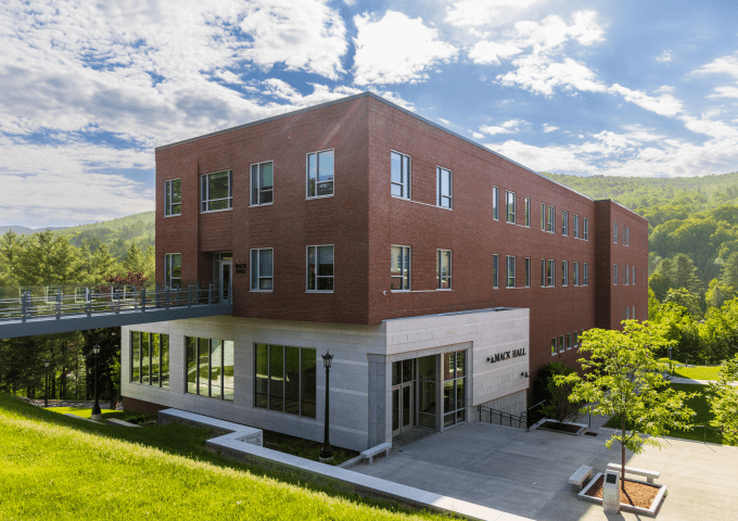Mack Hall, large rectangular building, with the Green Mountains in the background.