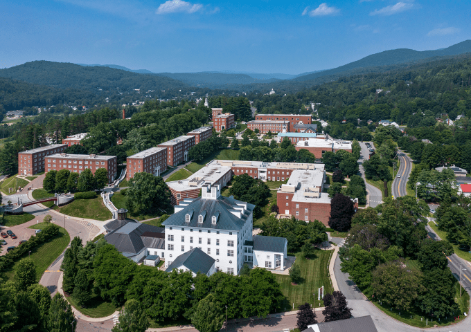 Aerial view of Norwich campus in the summertime with the library in the foreground and the Green Mountains in the background.