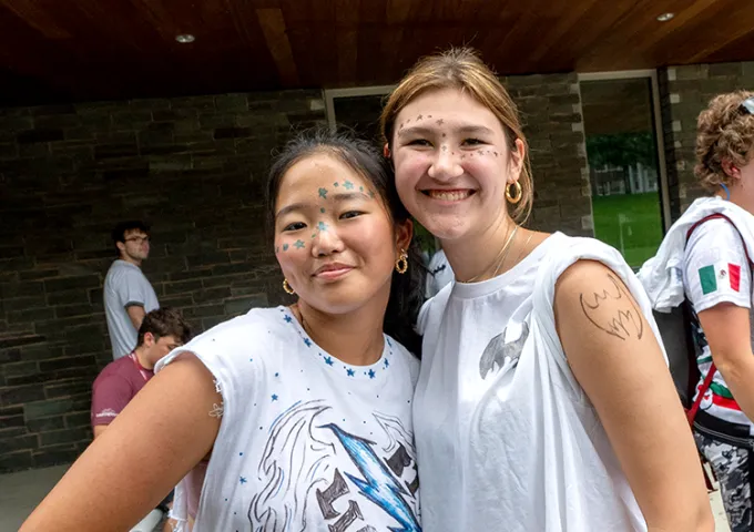 Two high school students smiling at the camera at summer camp.
