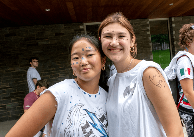 Two high school students smiling at the camera at summer camp.