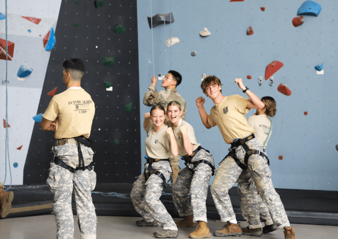 FLC attendees making fun poses and smiling together next to a large rock climbing wall.
