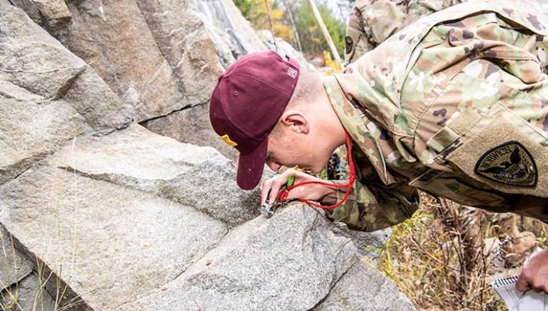Rook examining boulder up close for class outdoors.