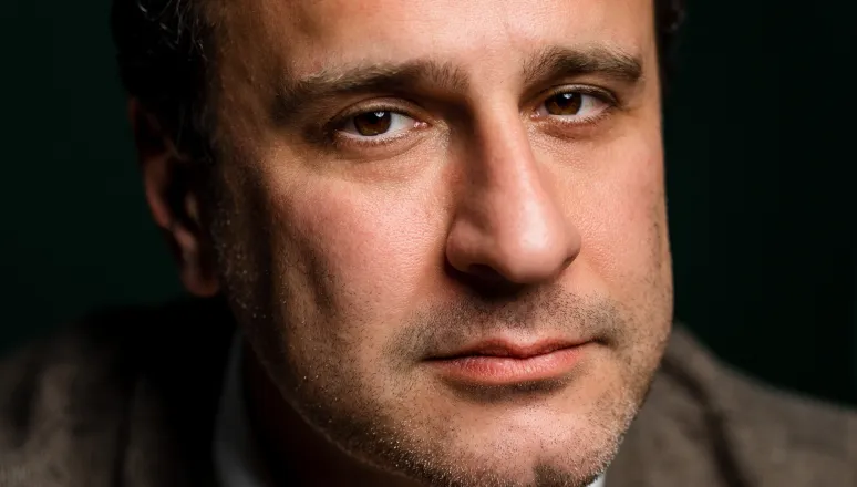 Close-up portrait of Simon Shuster against a dark background.