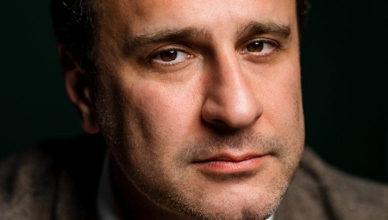 Close-up portrait of Simon Shuster against a dark background.