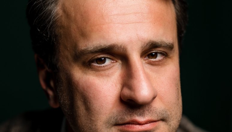 Close-up portrait of Simon Shuster against a dark background.