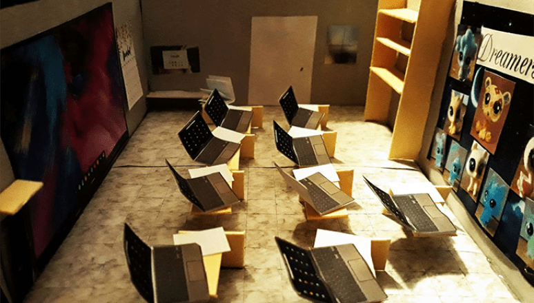 Architectural model of a computer lab with desks, laptops, a large screen, shelves, and colorful wall art.
