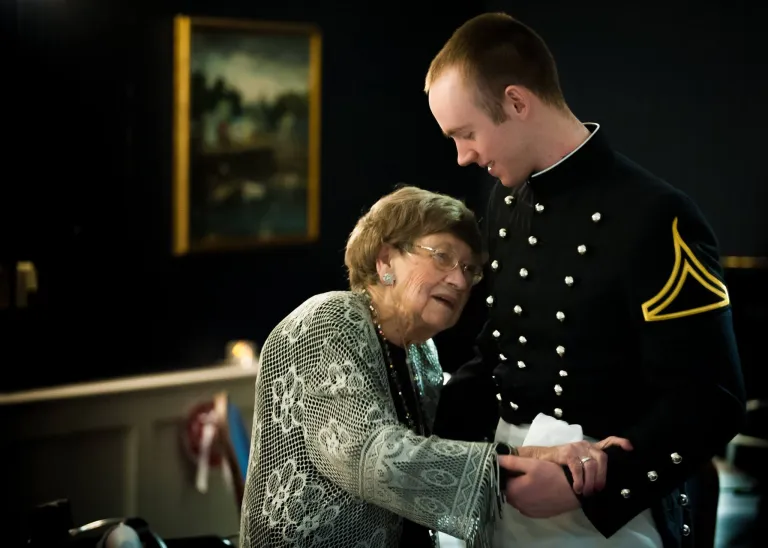A cadet dances with an elderly woman.