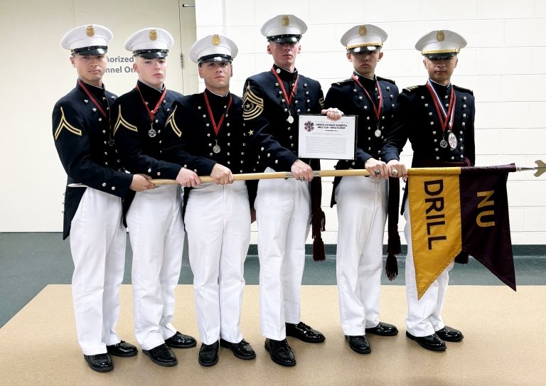 Group of six Norwich University cadets in uniform, holding a ceremonial banner and an award plaque.