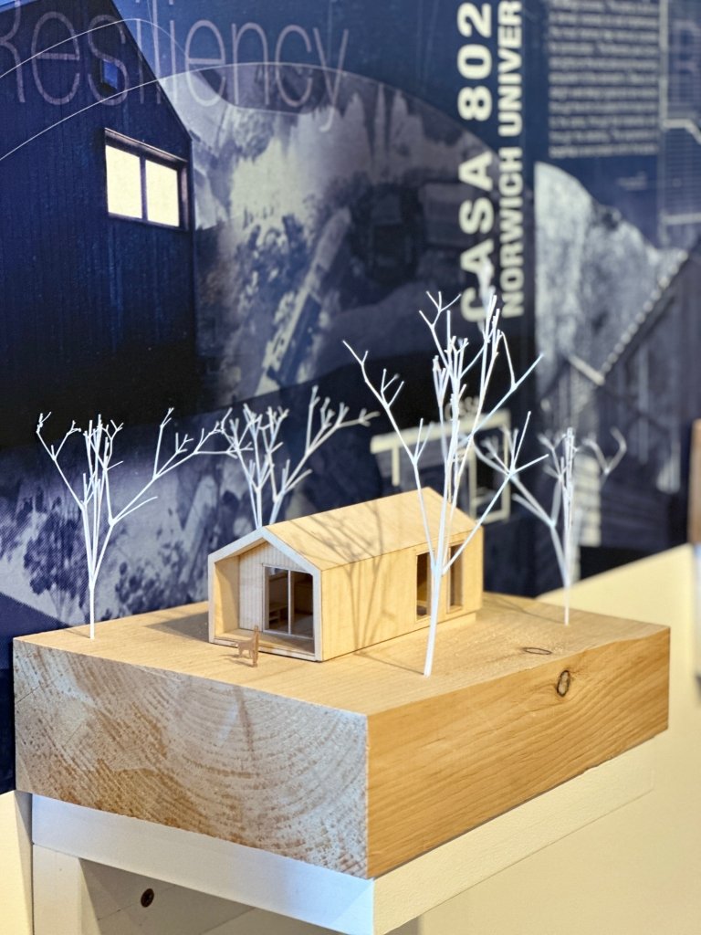 A scale model of a small house surrounded by white trees, displayed at an exhibit focused on resiliency.