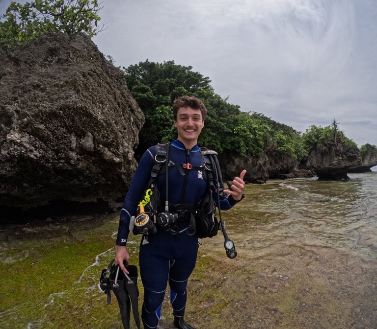 David Hamilton gives a thumbs up on a rocky shoreline before scuba diving.