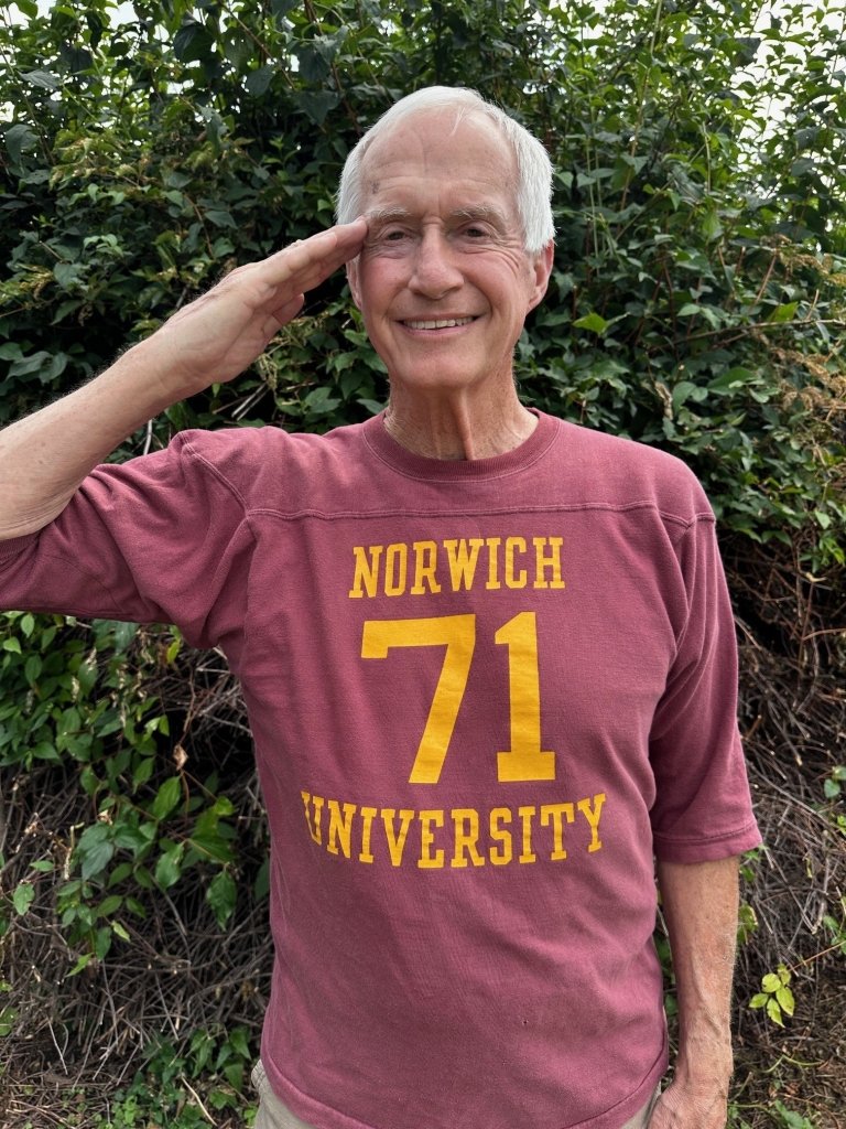 Greg May salutes while wearing an original 1971 Norwich University shirt.