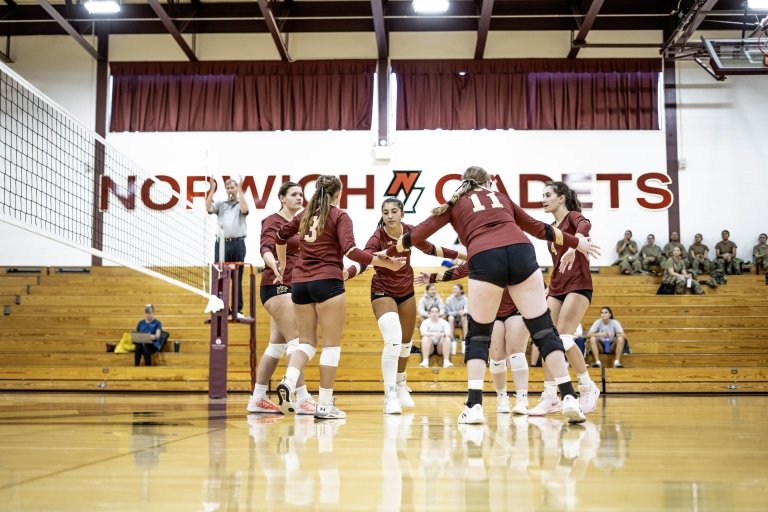 Women's volleyball celebrates on the court.