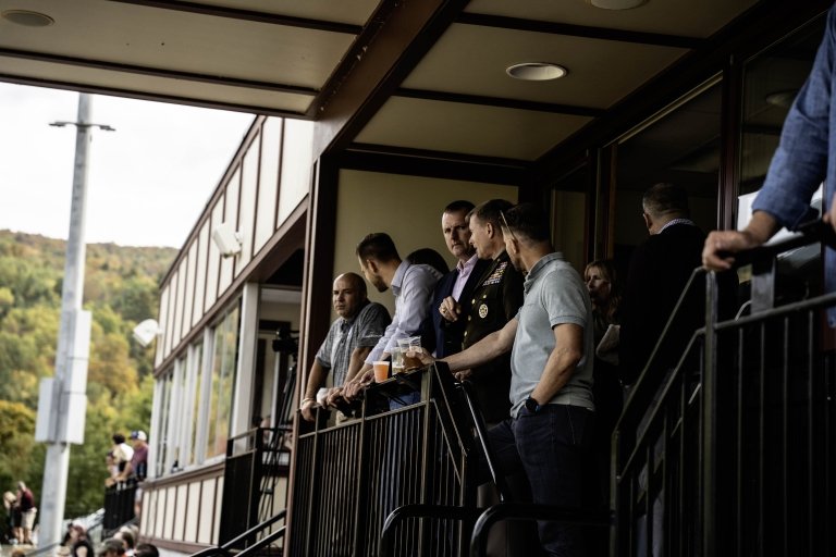 A group of military, Norwich, and NATO officials enjoy a football game from the President's Box.
