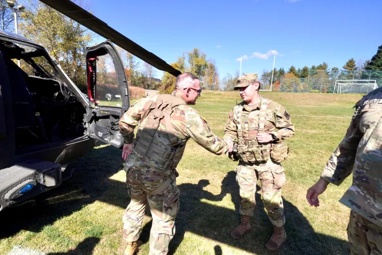 BG Adam Cobb shakes the hand of a cadet next to a Black Hawk helicopter.