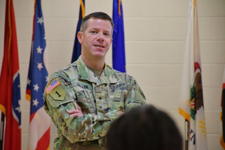 BG Miller stands in front of a crowd in uniform.