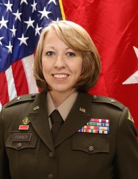A woman in Army uniform with medals smiles in formal headshot.