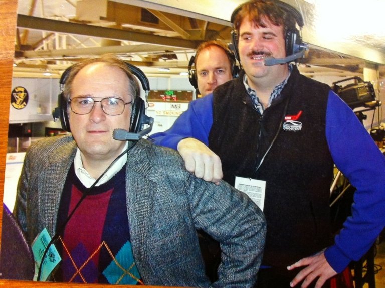 Two broadcasters smile while wearing their headsets.