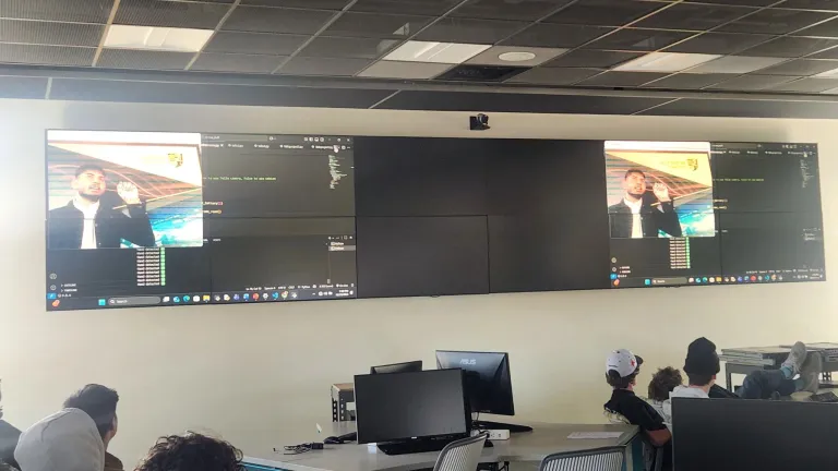 A student demonstrates AI on the screens in front of a classroom.