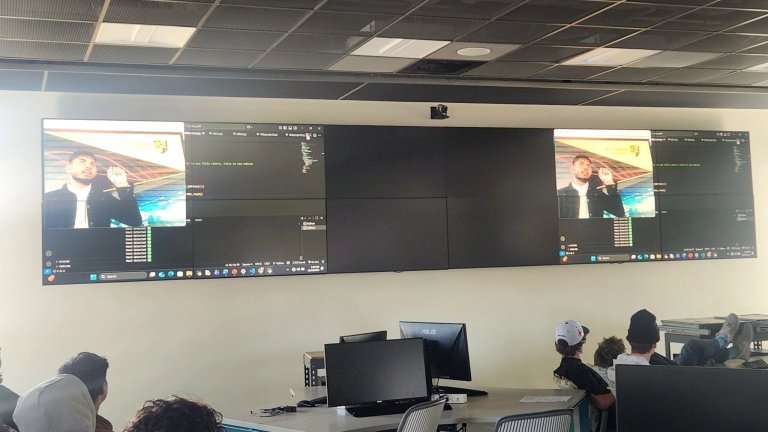 A student demonstrates AI on the screens in front of a classroom.