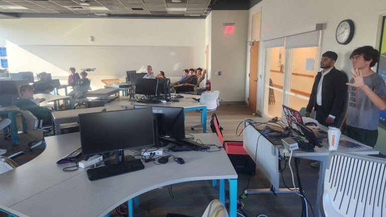 A student in a suit presents with a student next to him.