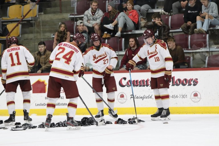The Cadet players gather socks on the ice.