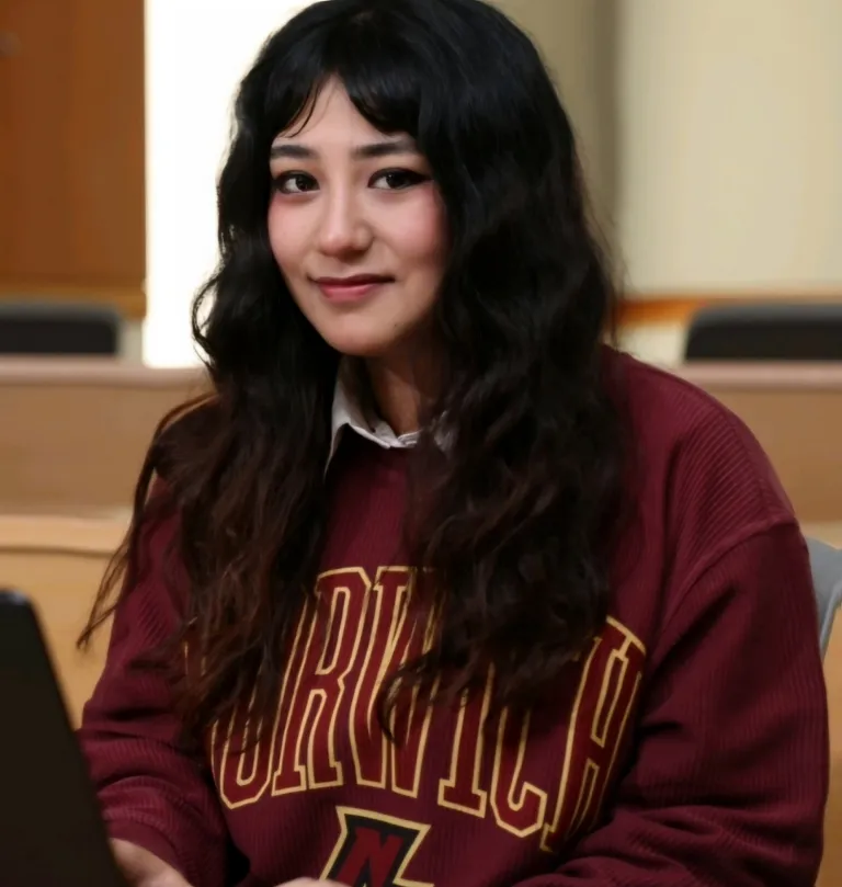 A woman in a Norwich sweater smiles at the camera.