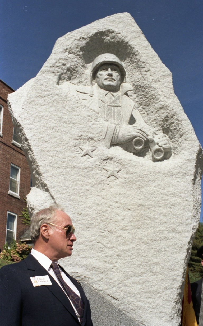 A sculptor stands next to a sculpture he completed of General Harmon.
