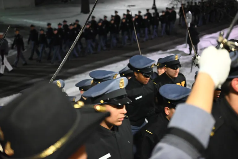 A close-up of cadets walking in file into a building.